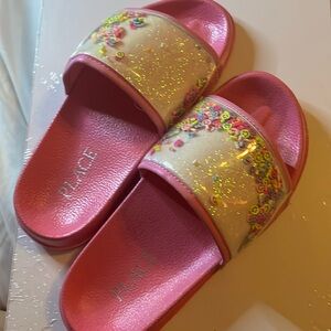 Pink slides that have a white strap with smiley faces in them